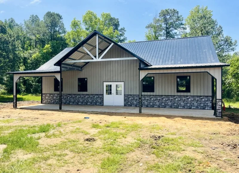 Barndominium with a stone wainscot, covered porch and metal roof