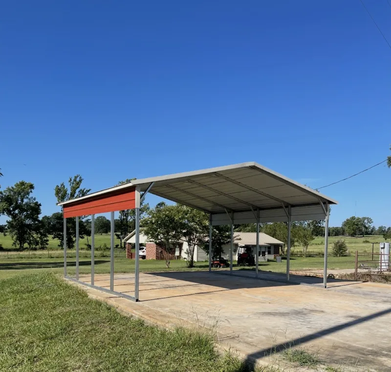 Open metal carport with a red and white roof over a concrete slab