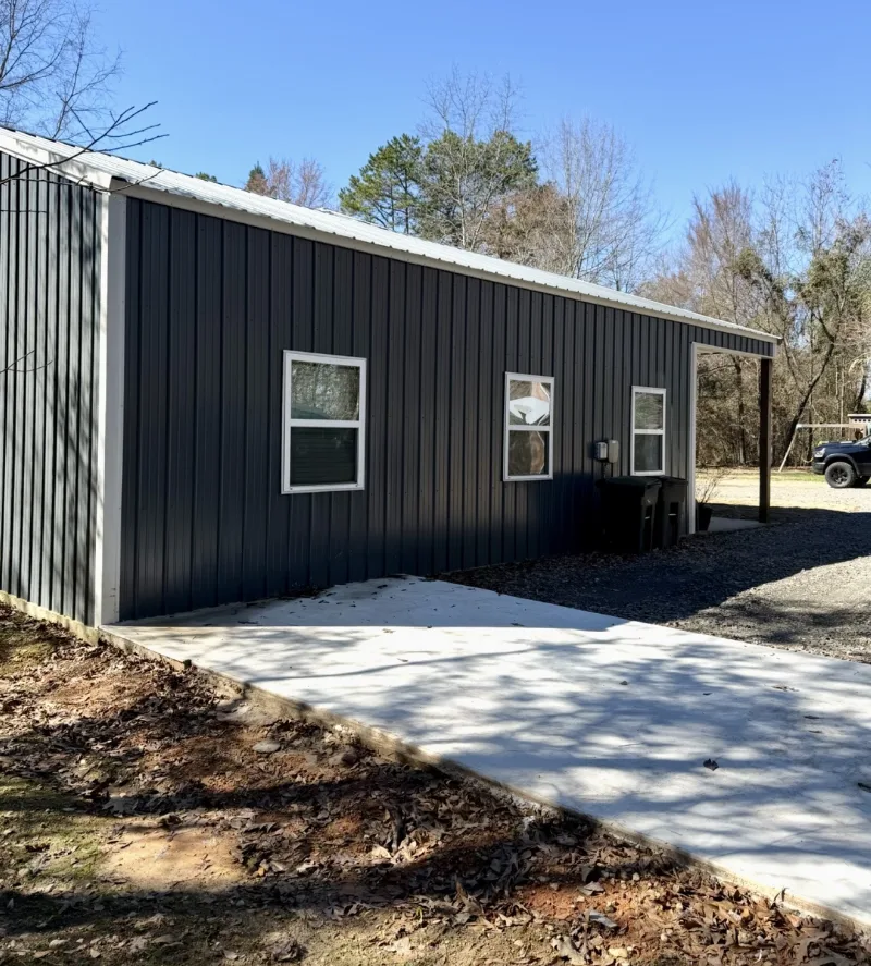 Charcoal metal building with windows and a new concrete walk