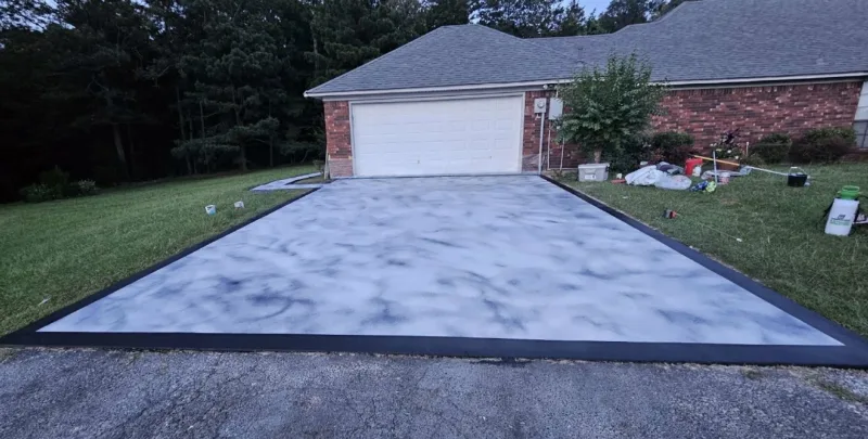 Driveway with a marbled grey and white coating leading to a brick house