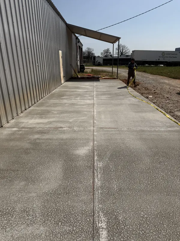Wide concrete apron running alongside a commercial metal building