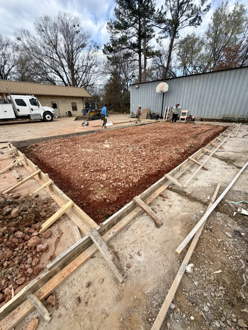 Formed slab with a compacted red base at a commercial lot, ready for a pour