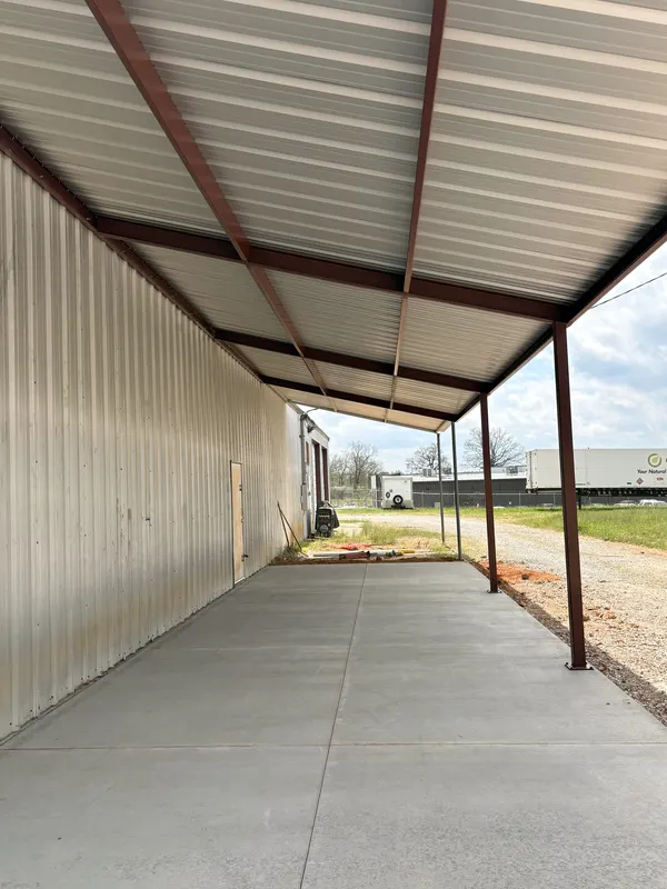 Long red iron covered walkway over a poured concrete path
