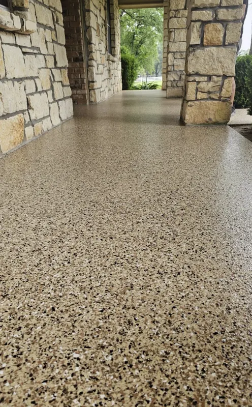 Epoxy flake floor in a stone-columned breezeway looking out to a lawn