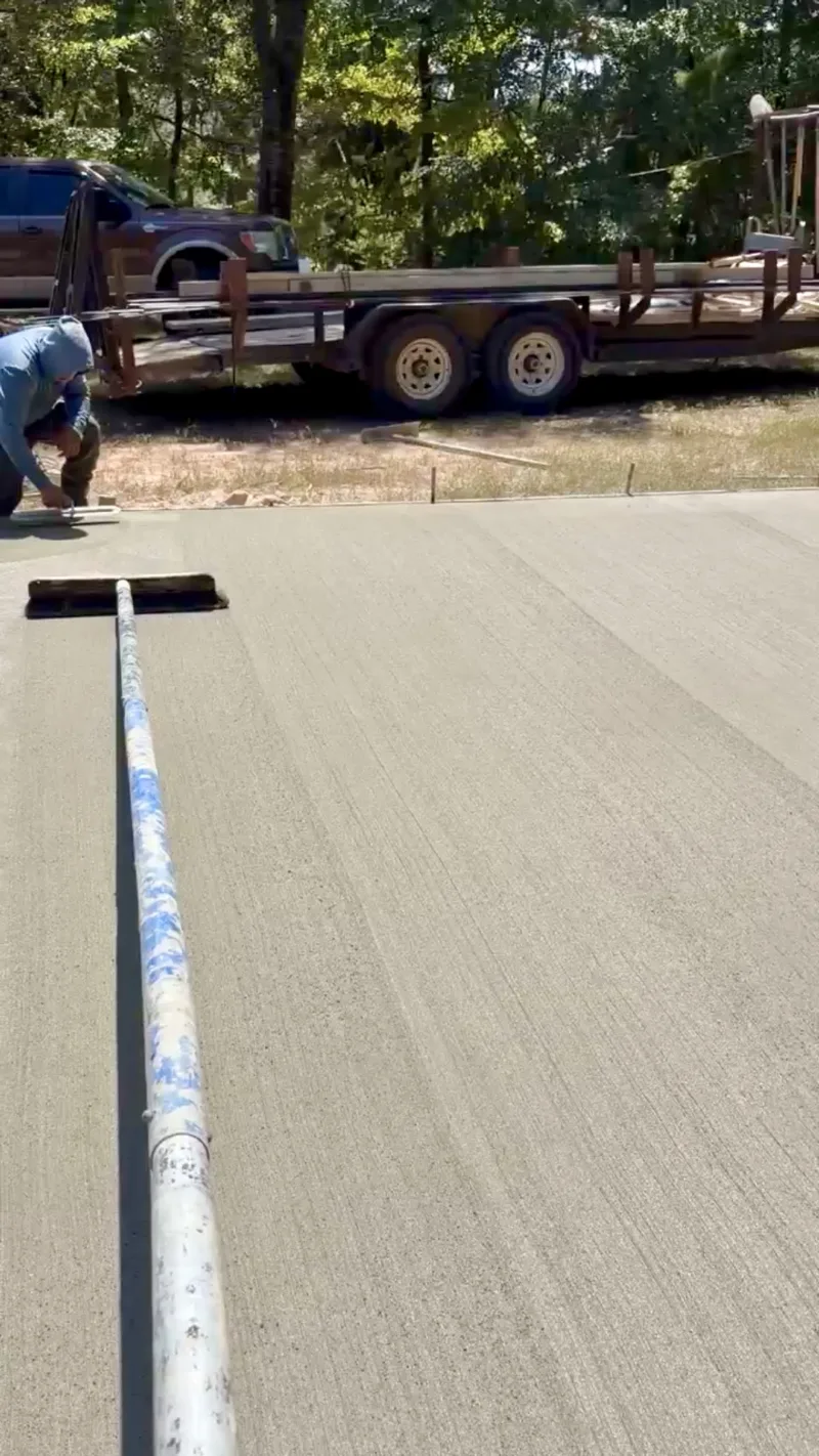 Freshly finished slab with a screed pipe laid across it and an equipment trailer behind