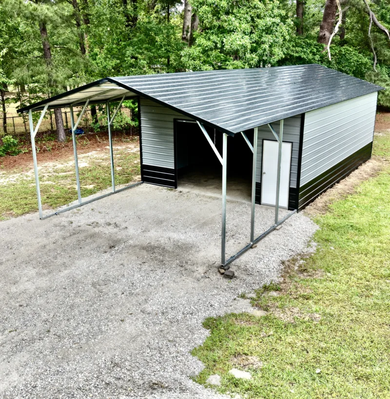 Two-tone metal garage with an open carport on the side over gravel