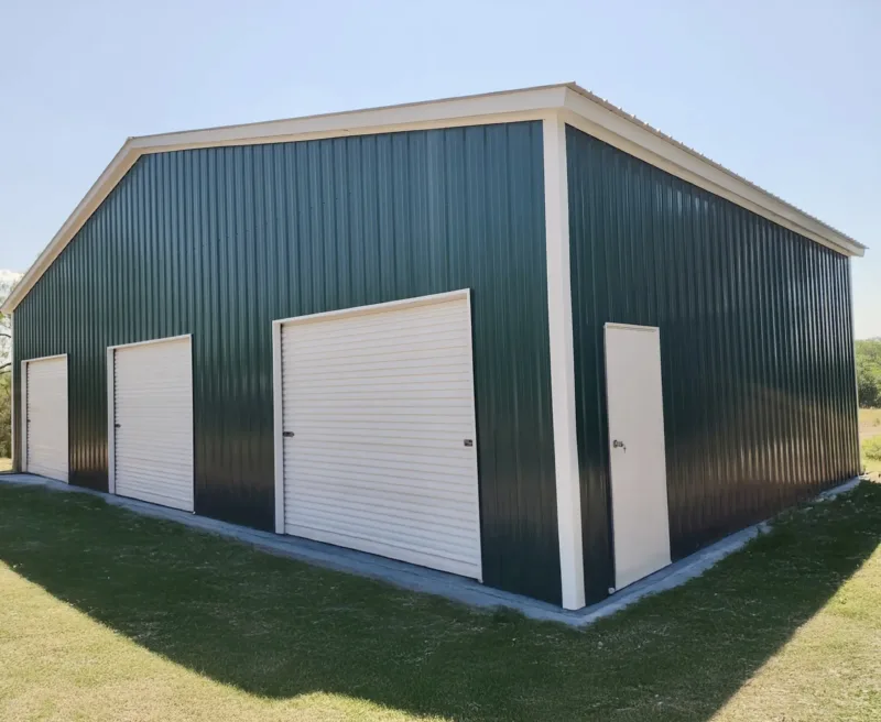 Green metal building with white trim and three roll-up doors