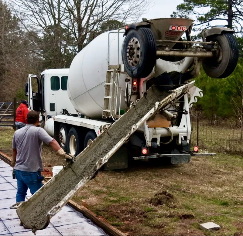 Worker guiding a ready-mix truck chute into slab forms