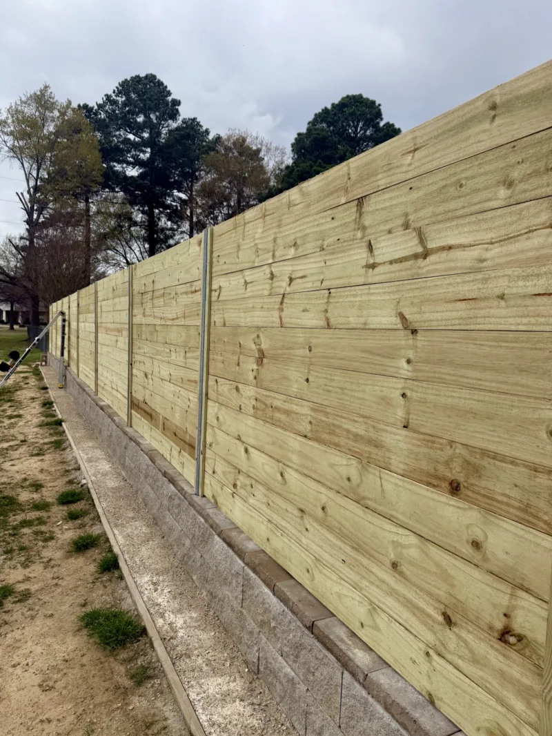 Wooden privacy fence set on a concrete retaining curb