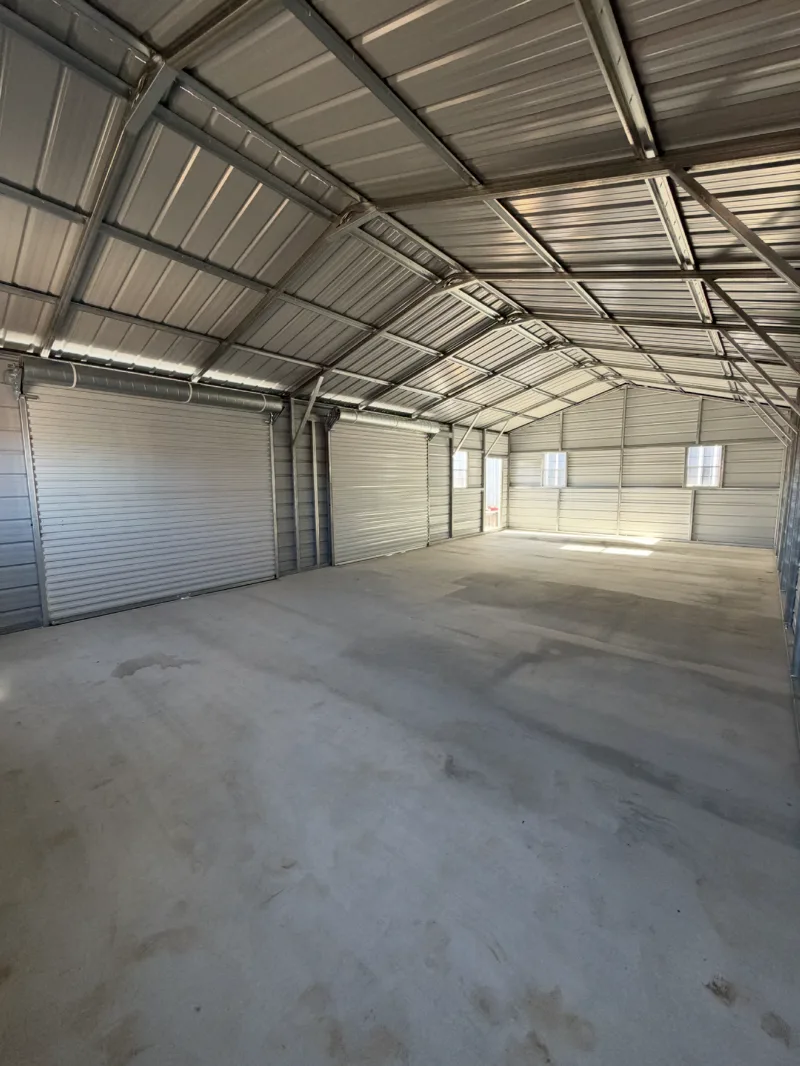 Inside a large metal shop with roll-up doors and a finished slab