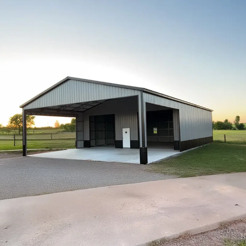 Metal shop with an attached open carport over a concrete drive at dusk