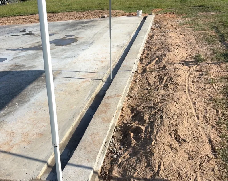 Finished concrete slab with a narrow drainage channel formed between the slab and a raised curb along its edge