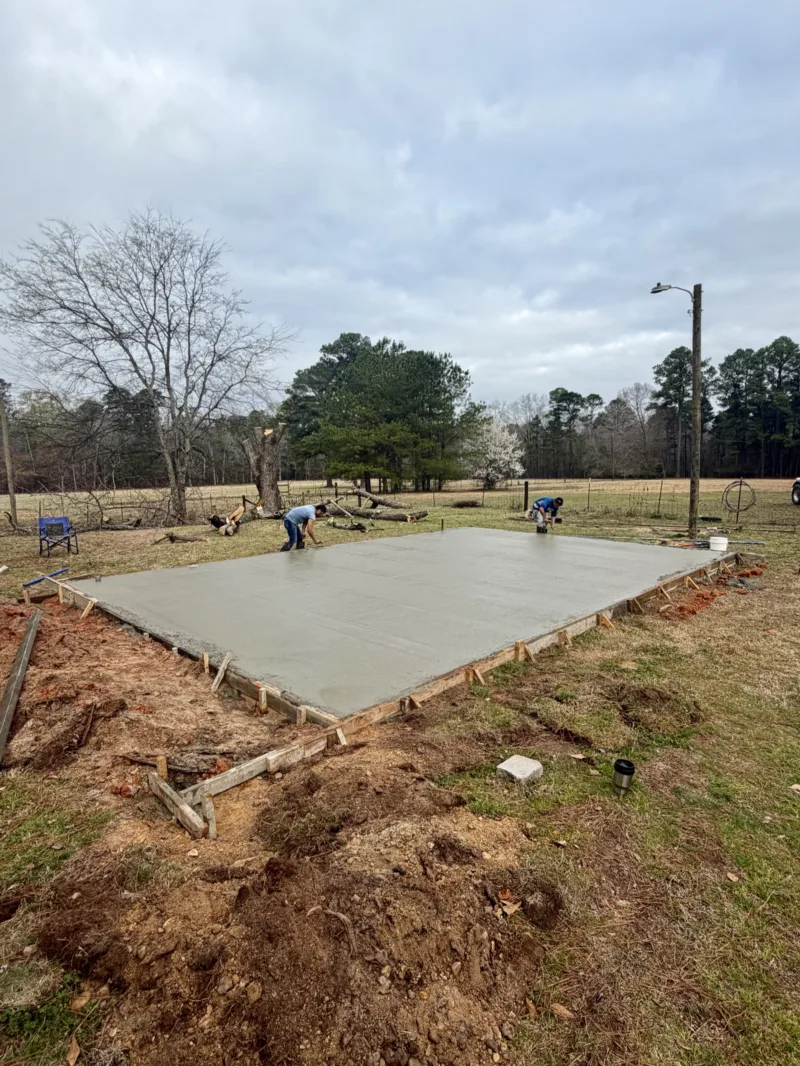 Crew finishing a fresh concrete slab in a pasture
