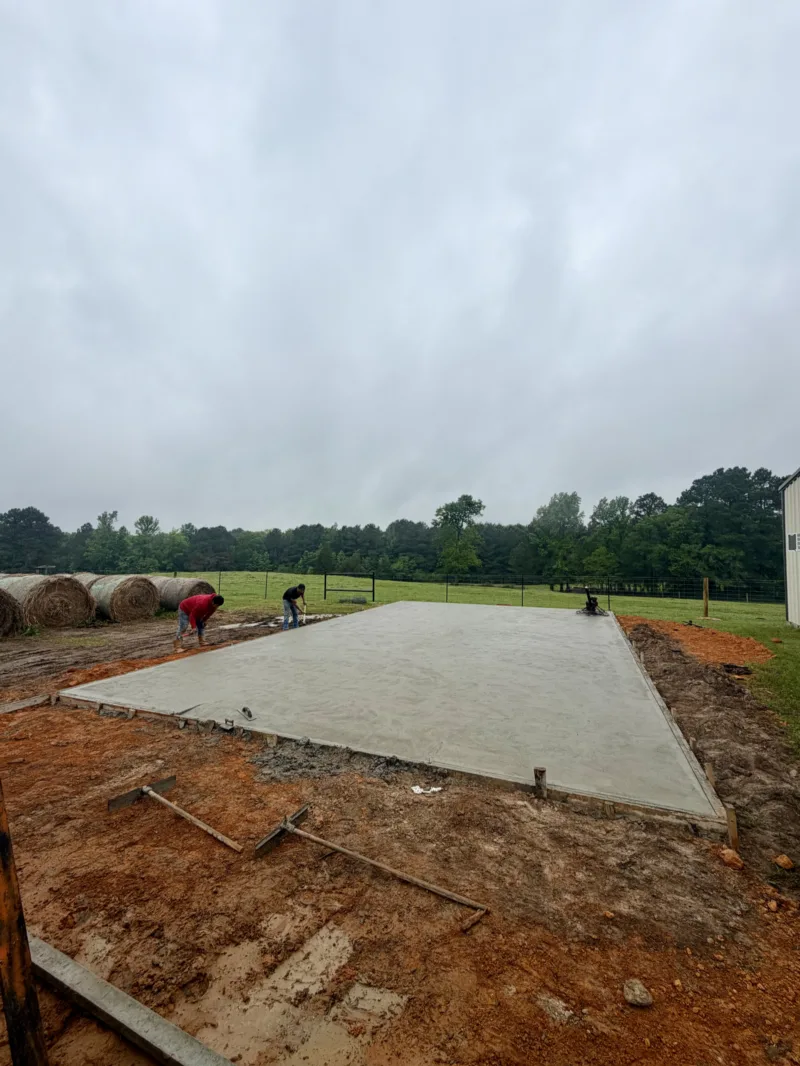 Crew placing a slab in a hay field under an overcast sky
