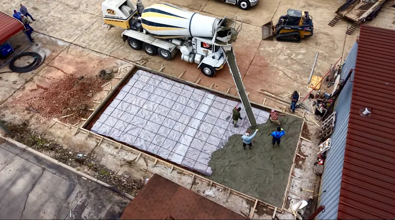 Crew placing concrete from a mixer truck and pump across a rebar grid