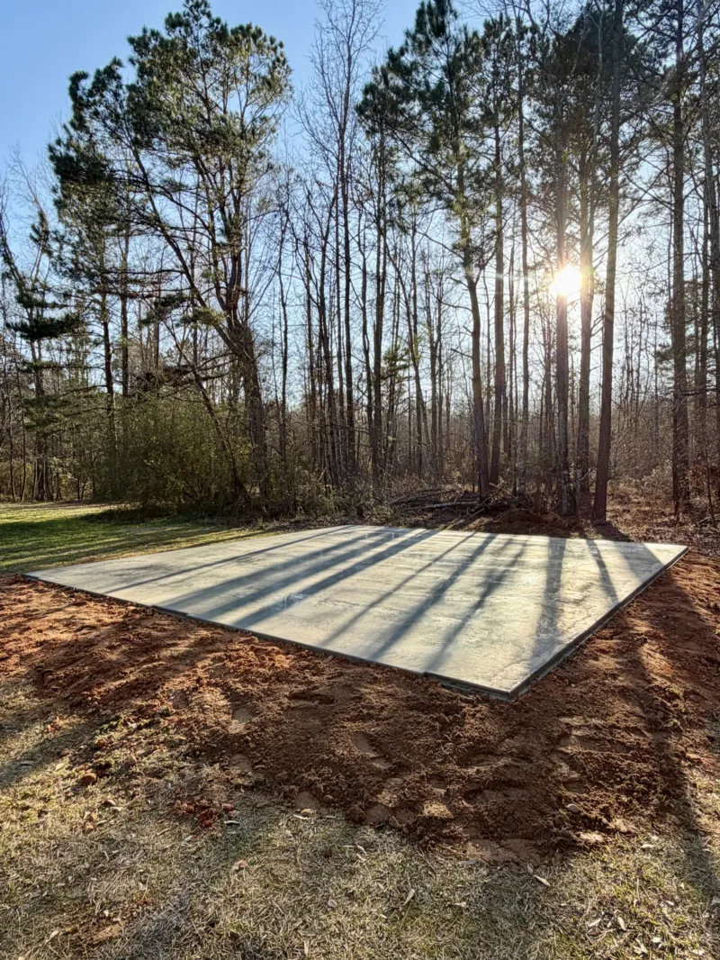 Finished slab in a wooded lot with the sun low through the pines