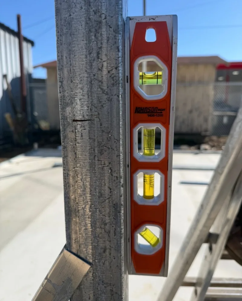 Torpedo level held against a galvanized square steel post, bubble centred