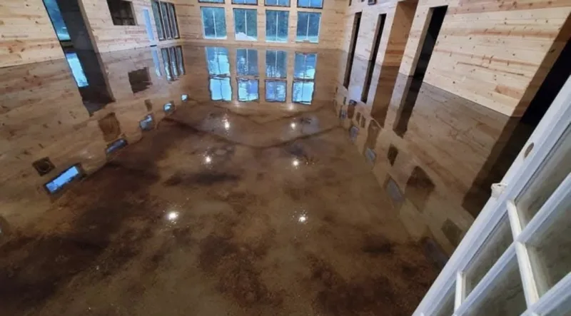Stained concrete floor in a large room with wood walls and tall windows