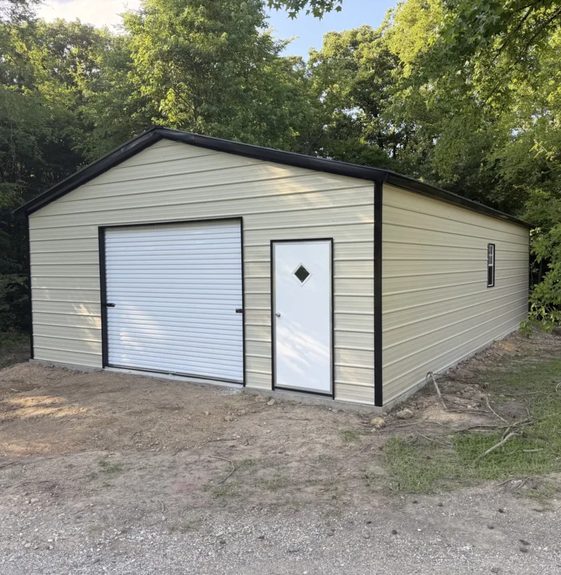 Tan metal garage with black trim, a roll-up door and a walk door