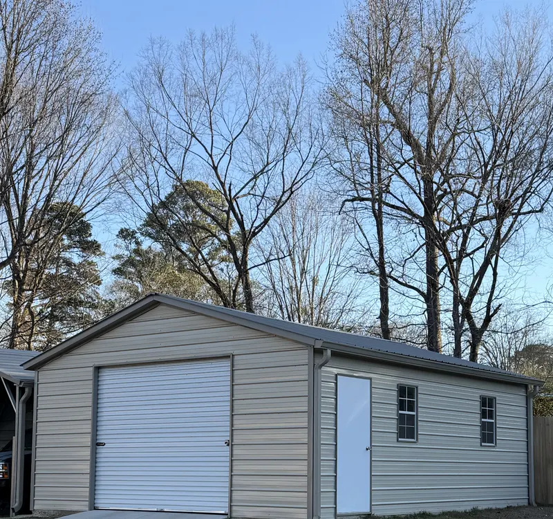 Tan metal garage with a roll-up door, walk door and two windows